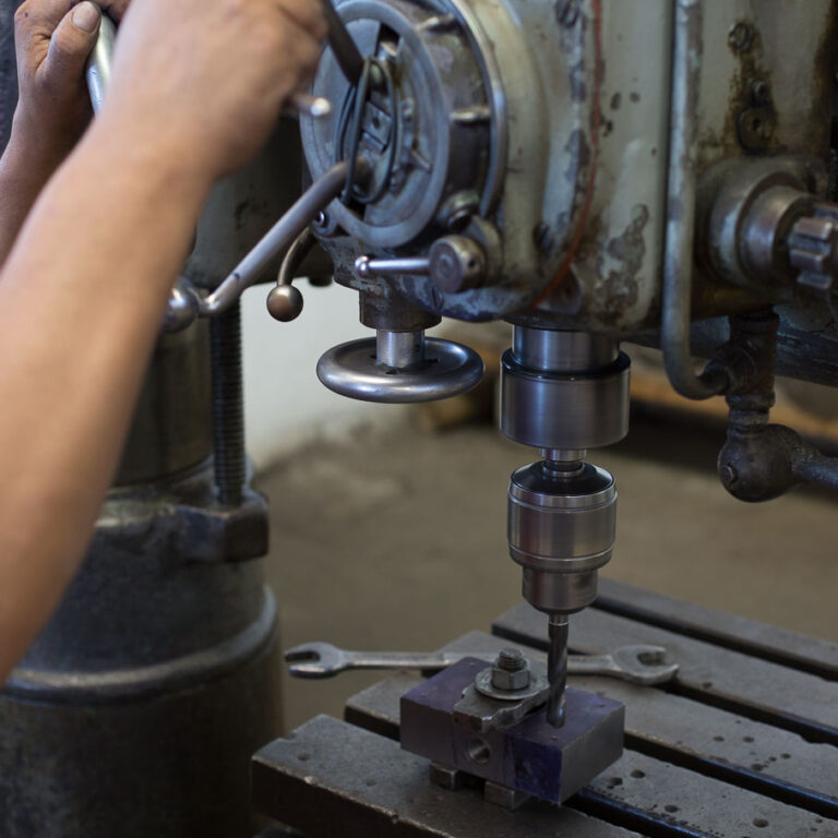 Taladro de columna perforando una pieza metálica en el taller de TSAI Cilindros