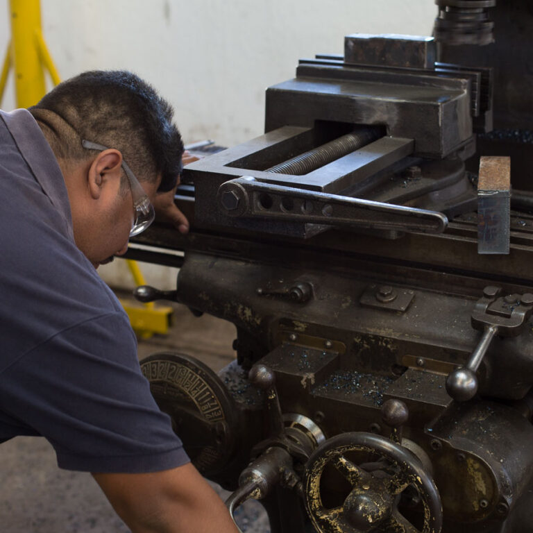 Técnico de TSAI Cilindros ajustando una fresadora en el taller